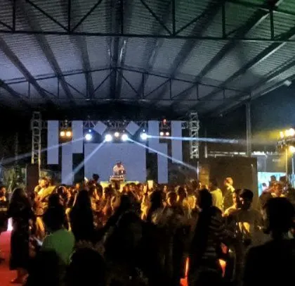 A full house at a corporate event, with a massive lighting rig and LED screen.