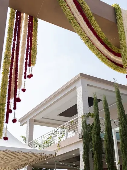 A low-angle shot looking up at the festive flower garlands decorating the entrance of a home for a traditional ceremony.