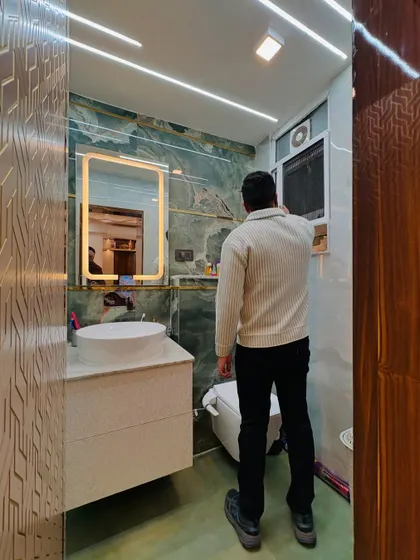 A full view of a compact yet luxurious bathroom. The design combines beautiful green tiles, a sleek vanity, and a backlit mirror to make the space feel larger and more elegant.