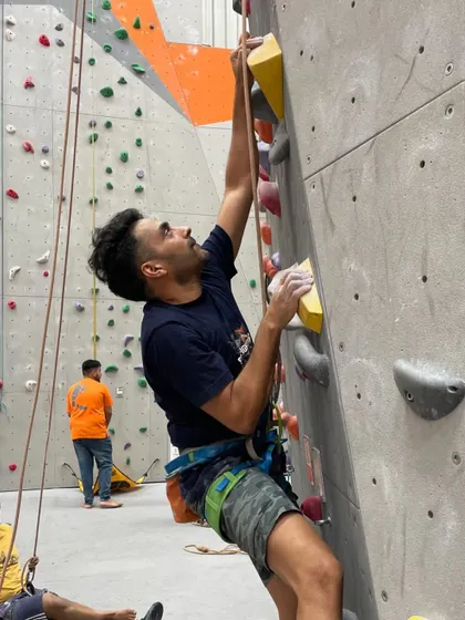 A climber reaches high for the next hold, fully focused on the route. Our gym provides the perfect environment to train and push your limits.