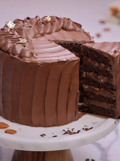 We create the ultimate indulgence with our chocolate almond cake. This rich, multi-layered chocolate cake is frosted with a silky chocolate buttercream and adorned with delicate gold leaf, offering a luxurious and classic dessert for Mother's Day.