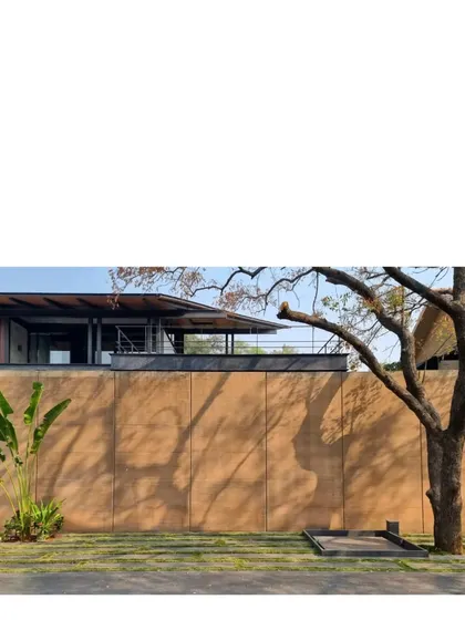 The strong form of a rammed earth wall at the Lakeshore house, with shadows from a nearby tree playing across its surface. The earth, taken from the site itself, gives the home a deep sense of belonging.