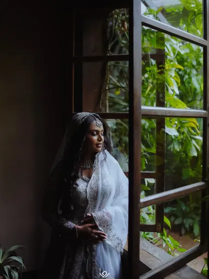 A pensive bridal portrait, with the bride looking out a large window, creating a moody and cinematic feel.