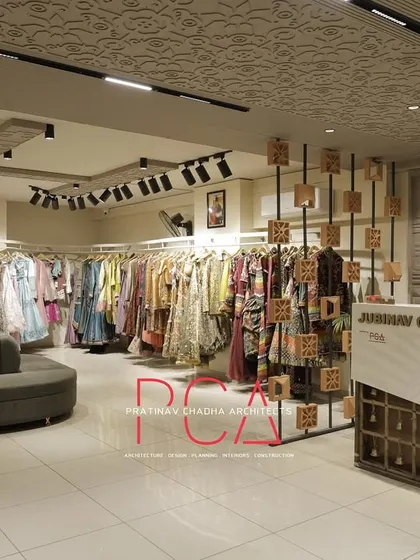 An overall view of the Jubinav Chadha Fashion Design Studio, showing the main retail floor with its central seating, custom reception desk, and curated clothing displays. The space is designed to feel open and luxurious, enhancing the customer journey.