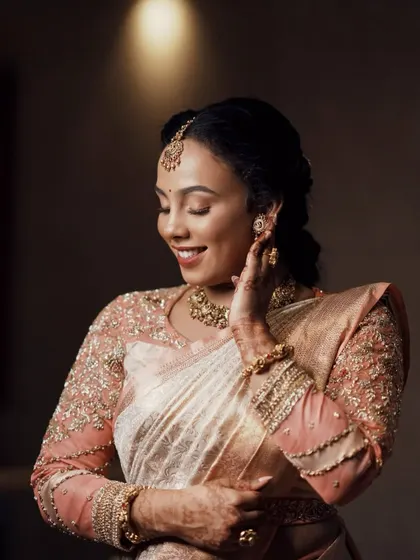 A close-up shot focusing on the stunning full sleeve of the pastel peach Kanjeevaram blouse, showcasing the detailed embroidery.