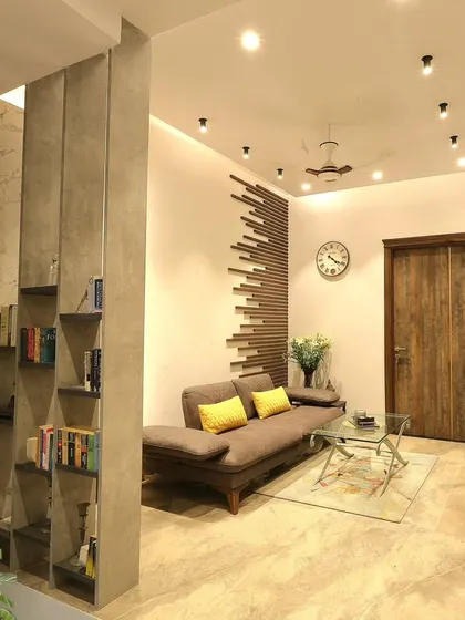 This family lounge in our Monochrome Oasis project in Noida was designed for cozy comfort. A custom bookshelf partition defines the space without closing it off, creating a perfect reading nook.
