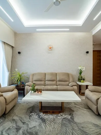 This perspective highlights the textured wallpaper and sculptural wall light that add character to the seating area. The arrangement of the recliners and sofa around a marble-top coffee table creates a cozy and conversational setting.