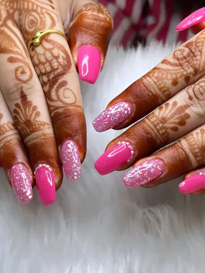 A vibrant and celebratory look, perfect for pairing with traditional henna. This set features bright pink nails with sparkling silver glitter accents and a delicate line of pearls at the cuticle.