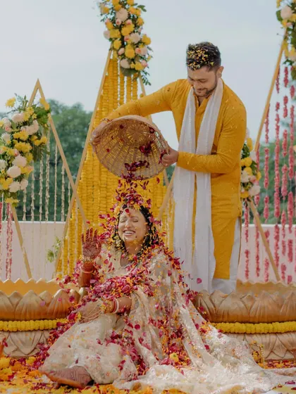 A joyous moment of a 'phoolon ki holi' during a Haldi ceremony, with the couple showered in flower petals.
