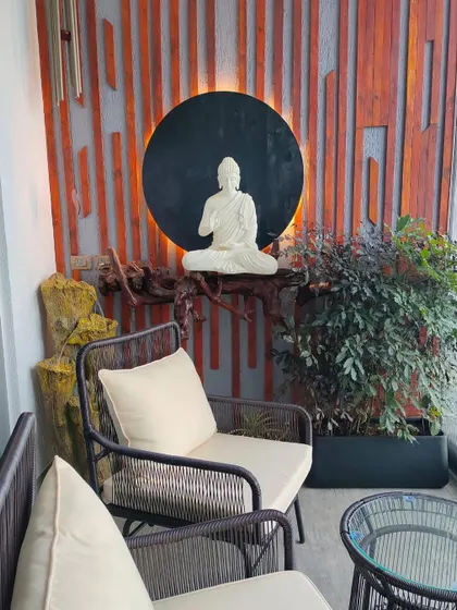 A wide shot of the Zen balcony, showing the seating area, the Buddha installation, and a wind chime. The composition creates a perfect oasis in the sky for relaxation.