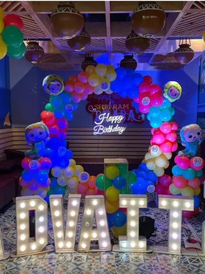 The full Cocomelon setup for Advait's 2nd birthday, showcasing the balloon arch, neon sign, and large marquee letters that make a big impact in the party space.