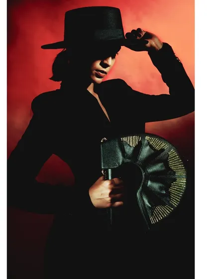 A dramatic silhouette shot from the 'Levels of Power' series. The model, wearing a wide-brimmed hat, is almost completely blacked out against a smoky red background, creating an icon of power and mystery.