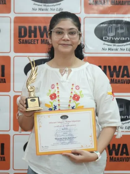 An adult student proudly holds her certificate and trophy.