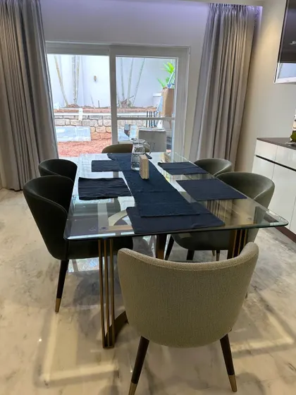 A glimpse into a beautiful residence featuring our custom dining set. The glass-topped table with its sculptural metal base and the elegantly curved dining chairs are tailored to the client's sophisticated taste.