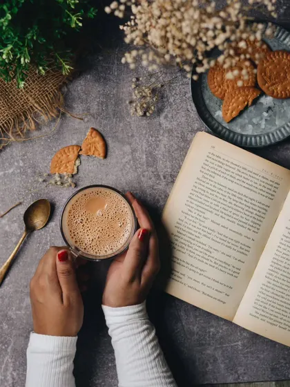 A cozy, rainy day scene with coffee, a book, and biscuits. This flat lay tells a story of relaxation and comfort, creating a mood that many people can connect with.