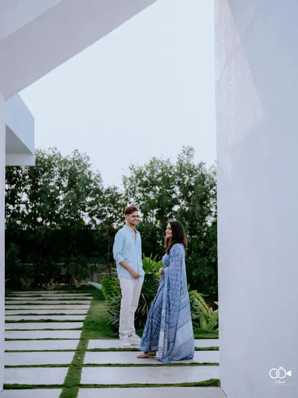 An architecturally framed shot of the couple standing in a modern walkway, their figures framed by clean white walls.