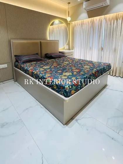A beautifully designed master bedroom with a full-height wardrobe and a bed with a custom back panel. The round mirror with a cove light above the dressing table adds a modern, stylish touch.