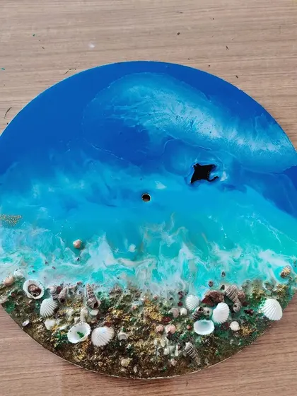 This completed resin art piece shows the beautiful blending of turquoise and white to create ocean foam, with a sandy shore made of real shells.