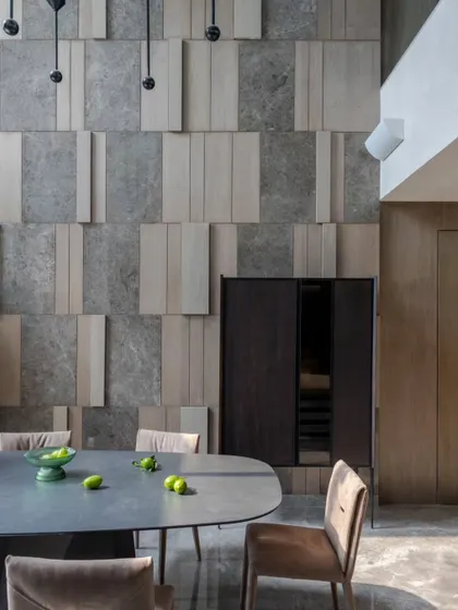 A closer look at the textured wall in the dining area. The interplay between the cool stone and warm wood is a recurring theme in our work, creating balance and depth.