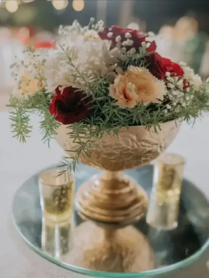 A classic and elegant centerpiece in a golden goblet-style vase, filled with red and white roses. This timeless arrangement is perfect for a formal dinner.