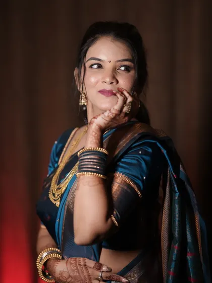 A playful, glamorous shot of the bride. The lighting highlights her contour and the rich color of her teal saree.