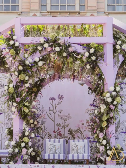 A close up of the pastel purple mandap, highlighting the intricate floral arrangements and the custom printed botanical backdrop that adds a whimsical touch.