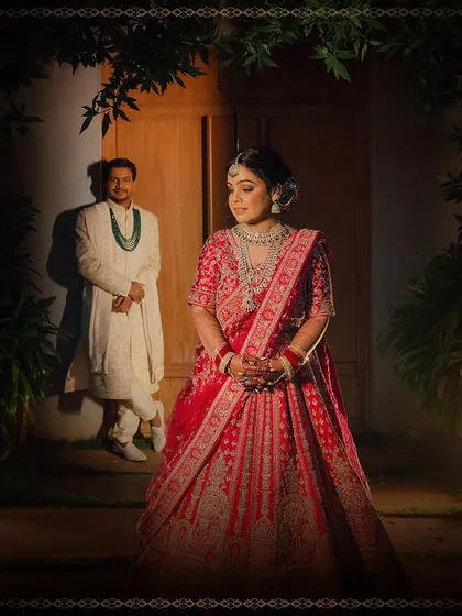 A dramatic and artistic portrait of the bride and groom. The lighting creates a moody and romantic atmosphere, highlighting the bride's regal presence.