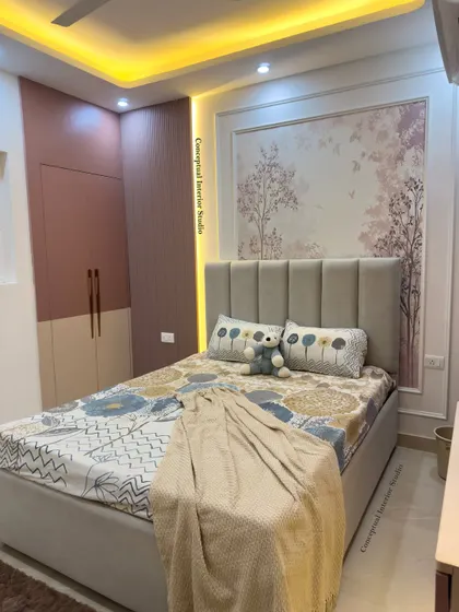 A glimpse of a 3BHK bedroom interior. The design features a soft color palette, a beautiful wallpaper mural behind the bed, and a two-tone wardrobe.