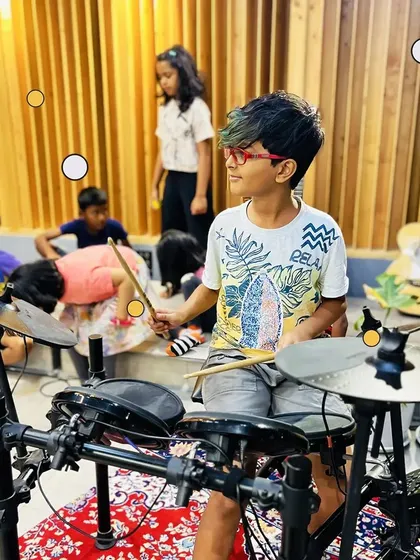A young camper gets his first taste of playing the drums. Our camp lets kids try out various instruments to discover what they're passionate about.