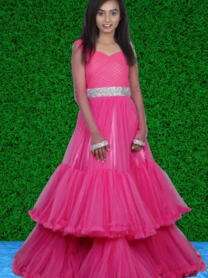 A vibrant pink tiered gown with sheer long sleeves and a silver belt. This is a fun, Barbie-inspired look for parties or themed shoots.