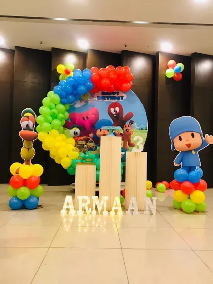 A Pocoyo-themed third birthday party. The setup features characters from the show on balloon columns and a backdrop with a colorful balloon garland.