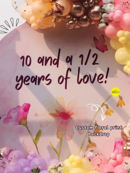 A detailed look at the custom floral print backdrop. The soft, watercolor-style flowers and butterflies created a "garden of love" theme for this special anniversary and half-birthday celebration.