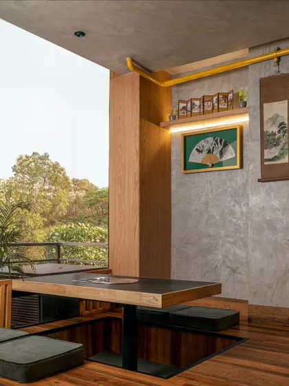 Natural light floods this corner of Seoul, highlighting the contrast between the smooth concrete walls and the warmth of the wooden architecture. The sunken table overlooks the outdoors, offering a serene dining experience that connects guests with nature.