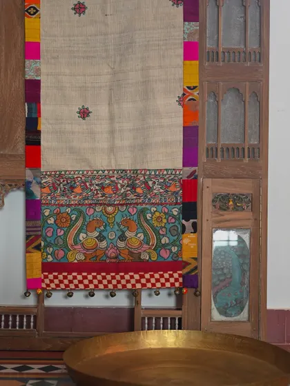 The full runner displayed against a vintage wooden jharokha, showcasing its length and artistry.
