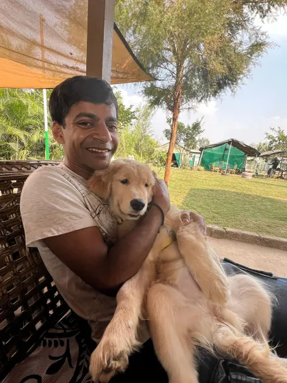 A guest holds a cute Golden Retriever puppy, both looking happy and relaxed in our outdoor seating area.