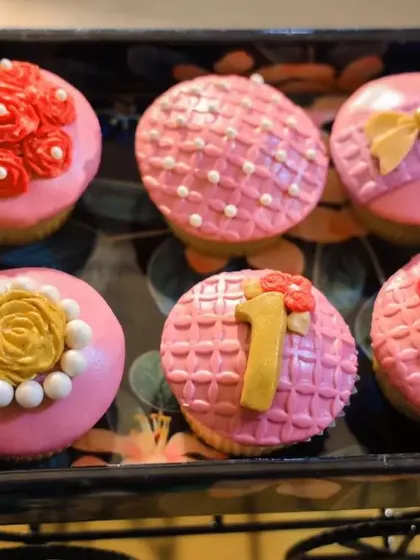 It's all in the details. These custom-designed cupcakes were part of the dessert table, featuring intricate fondant work with flowers, bows, and a number '1' to celebrate the special milestone.