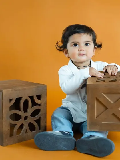 This little one is playing with wooden blocks against a warm orange background. We use simple toys to capture natural, playful moments.