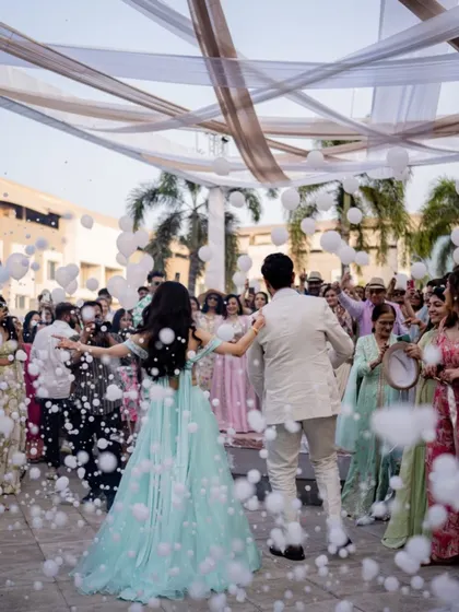 The couple makes a grand entrance, dancing through a cloud of bubbles surrounded by their happy friends and family.