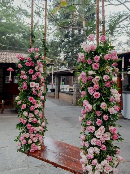 A swing heavily decorated with beautiful pink roses.