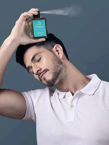 A male model sprays a perfume bottle above his head, creating a refreshing and dynamic image for a fragrance ad.