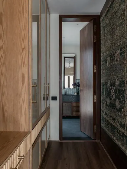 A view from the walk-in closet into the bathroom at Pràna. The custom wood cabinetry and the glimpse of the patterned rug on the wall show our love for layering materials and textures.