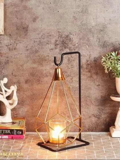 This geometric candle holder features a diamond-shaped wireframe cage hanging from a simple black stand. It's a modern and minimalist way to add the warm glow of candlelight to your tabletop.