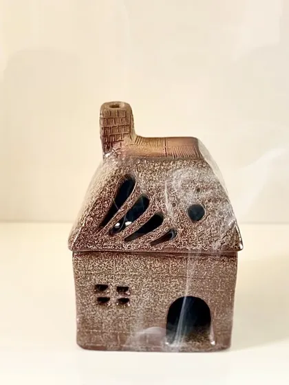 Another view of the student-made house incense burner, showing the detailed texture on the roof and the small windows.