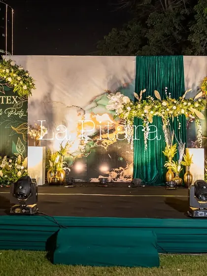 A full view of the main stage setup for the Inditex party at night. The combination of the printed backdrop, dramatic lighting, and floral decor created a captivating focal point for the evening.