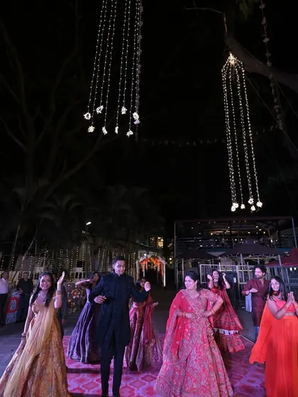 A full dance floor with the couple and their guests enjoying the Sangeet performances under a canopy of beautiful hanging lights.