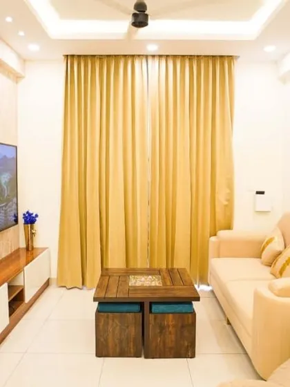 A bright and modern living room setup with a comfortable beige sofa and a striking TV wall. The geometric partition with gold mirror inlays adds a touch of glamour and visually separates the space.