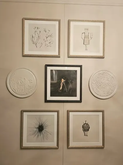 A straight-on view of the gallery wall installation. The combination of square and round frames, along with different art styles, creates a dynamic and balanced composition.