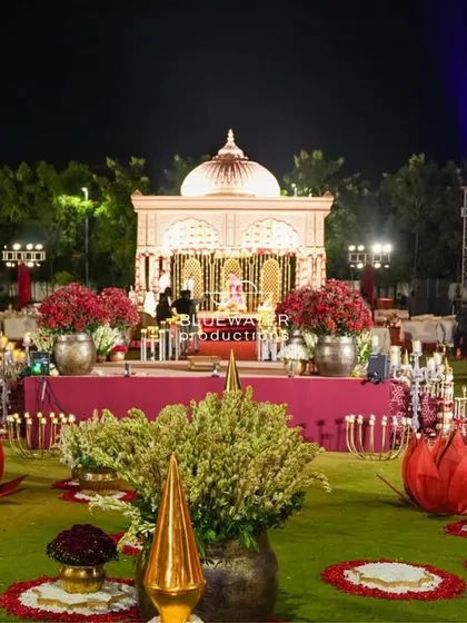 A breathtaking view of a traditional red-and-gold wedding setup, with the temple-inspired mandap as the centerpiece of the sprawling lawn.