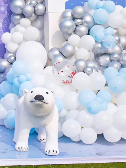 A small polar bear prop nestled among the balloon garland, a cute detail that adds depth and charm to the decor.