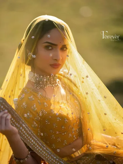 A stunning portrait of the bride under her yellow veil. The golden hour light makes her skin and makeup look absolutely ethereal.